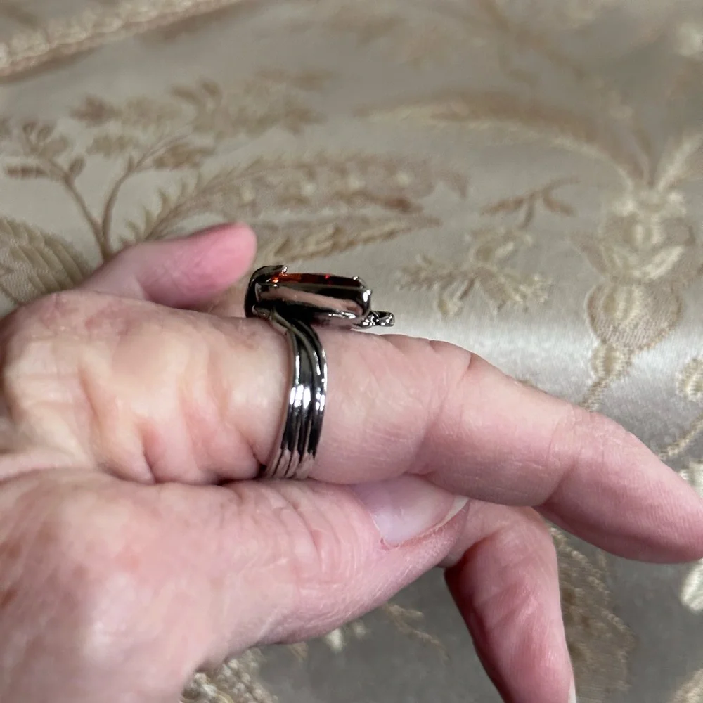 Ring in silver metal intricate with teardrop shaped amber color stone